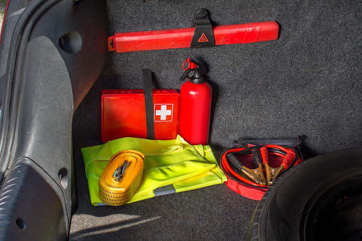 The interior of the trunk of the car in which there is a first aid kit, fire extinguisher, warning triangle, reflective vest, starter cables and tow rope